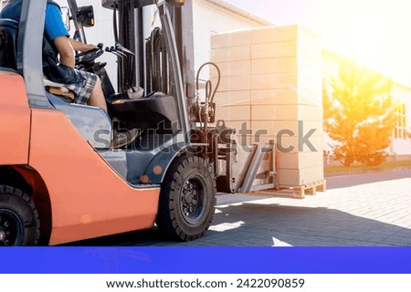 Forklift vehicle manipulating goods in logistic area outside warehouse.
