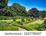 Formal French garden with topiary, flower beds, hedges, lawns and tall trees around castle Menkemaborg, Uithuizen, province of Groningen, the Netherlands
