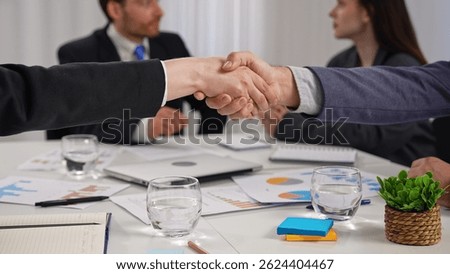 A formal handshake between two professionals against an office background, symbolizing mutual agreement and cooperation.