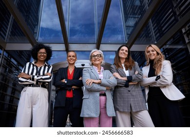 Formal work group of smiling happy diverse business only women standing in a row looking cheerful to camera together proud expression outdoor. Professional empowered females leaders posing confidence - Powered by Shutterstock