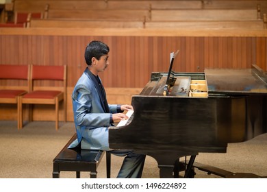 Formally Dressed Young Boy Playing The Grand Piano At His Piano Recital