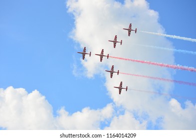 Formation of six stunt jets flying on cloudy blue sky leaving red and white smoke trails - Powered by Shutterstock