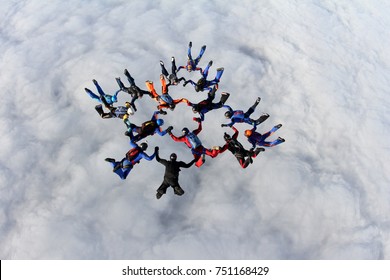 Formation skydiving above white clouds.