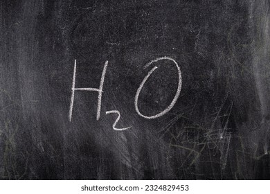 The formula of water written in chalk on a black chalk board