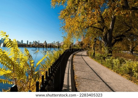 Forografia de un paseo al lado del Jacqueline Kennedy Onassis Reservoir, del Central Park en un dia de otoño. Los amarillos y verdes contrastan con el azul del embalse construido entre 1858 y 1862.