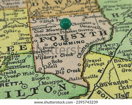 Forsyth County, Georgia marked by a green tack on a colorful vintage map. The county seat is located in the city of Cumming, GA.