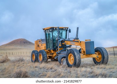 Fort Collins, CO, USA - March 31, 2022: Deere 770D motor grader at Colorado foothills used for dirt road maintenance, early spring scenery at dusk.
