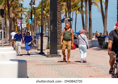 Fort Lauderdale Beach, Florida, USA - March 5, 2021: Older Gentleman Tourist Walking Down Boardwalk Pavers During Spring Break Near The Water And Sand With Palm Trees And Street Traffic Signs.