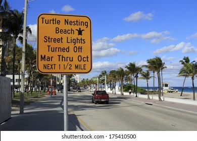 FORT LAUDERDALE, FLORIDA - JANUARY 23, 2014: A large yellow and black sign along A1A warning people visiting the beach that street lights are off at night March through October. 