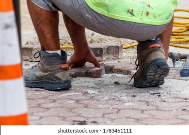 Fort Lauderdale, Florida / USA - 2/27/2019: Construction Worker Installing Concrete Red Block Pavers With Safety Cones, Buckets For Cement, Grout And Yellow Electrical Cables For Power Tools.