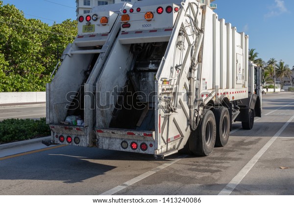 Fort Lauderdale, Florida USA - June 01, 2019:\
Garbage truck to collect municipal solid waste in early morning on\
a sunrise. Garbage man on\
duty.