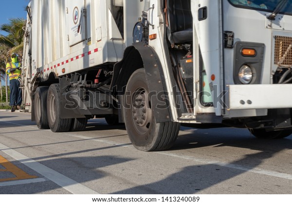Fort Lauderdale, Florida USA - June 01, 2019:\
Garbage truck to collect municipal solid waste in early morning on\
a sunrise. Garbage man on\
duty.