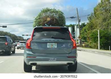 Fort Lauderdale, Florida, USA - November 22, 2021: Christmas Tree Tied Onto Gray Volvo XC90 T6 (4 Cylinder SUV) With American Flag With Blue Line Sticker That Represents Support Of US Police Officers.