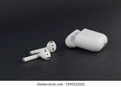 Fort Myers, FL / USA - 12/27/19: Apple Air Pods wireless Bluetooth headphones with wireless charging case minimalist trending tech Macro shot on black background, Copy Space