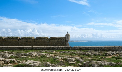 a fort wall with a small tower over the ocean