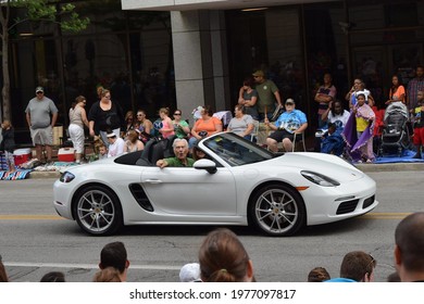 Fort Wayne, Indiana, USA - July 10 2016: An Old Man Riding In A White Porsche Convertible Pointing At The Crowd During The Three Rivers Day Parade In Downtown Surrounded By Tall Buildings.