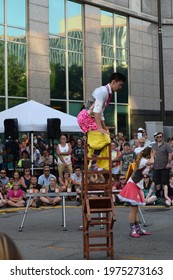 Fort Wayne, Indiana, USA - June 25 2016: Talented Chinese Acrobat Standing And Balancing On Precariously Stacked Chairs Wowing An Amazed Crowd At Busker Fest In Downtown.