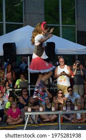 Fort Wayne, Indiana, USA - June 26 2016: A Girl Balancing And Walking On Glass Bottles Across A Balance Beam High Off The Ground At Buskerfest In Downtown.