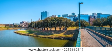 Fort Worth panoramic city skyline, buildings, and walking trails over the Trinity River Bridge, a cityscape with natural open space in Texas