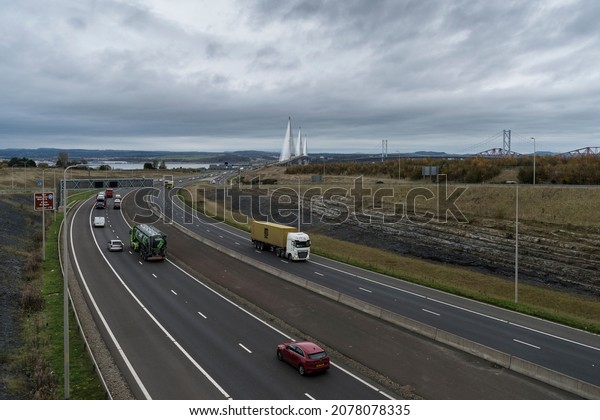 Forth Bridge Queensferry crossing, Scotland -
November 16 2021: moving traffic on M90 motorway in daylight
looking north with Queensferry crossing and other road and rail
bridges in background.