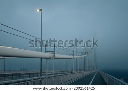 Forth Road Bridge covered in thick fog in the early morning and a burning lantern. Scotland, United Kingdom
