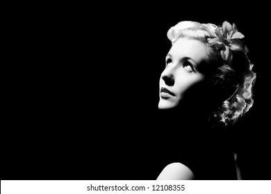 Forties hollywood black and white a beautiful woman stares right out of frame. Minimal lighting and strong contrast copy space to left