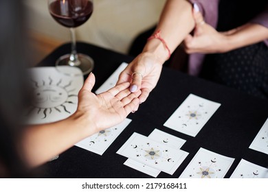 Fortune teller asking young woman to give her hand for palm reading