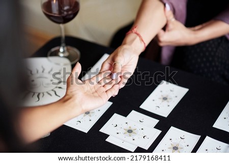 Fortune teller asking young woman to give her hand for palm reading