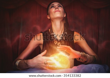 Fortune teller forecasting the future against red curtains