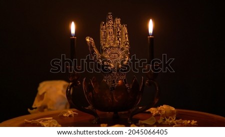 Fortune teller hand or palmistry on the witch table with animal bones. Palmistry with black palm and candles in the candelabra. Magic alchemy spirituality symbol. Palm reading in mystic, occult room.