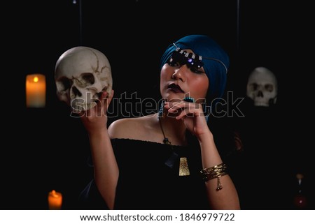 Fortune teller holding and looking skull. Psychic speaking to the dead using human skull in ritual. Stock photo © 