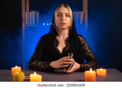 Fortune teller magical woman reading future on tarot cards. Ritual candles burning, seance, smoke.