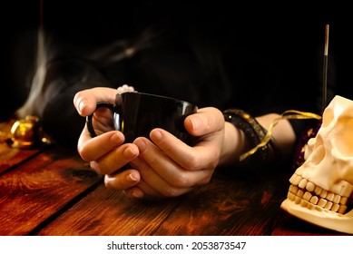Fortune teller or oracle with a black cup in hand for fortune telling on the coffee grounds. Psychic readings and the concept of clairvoyance - Shutterstock ID 2053873547