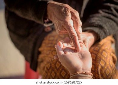 The fortune teller reads a fortune line on the palm or the hand of a mysterious woman. Concept of palmistry,Helping hands, care for the elderly concept.