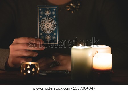 Fortune teller with a tarot card in hand concept.