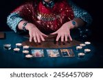 Fortune teller with tarot cards on table near burning candles.