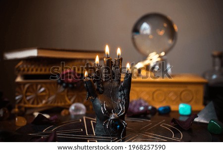A fortune teller, witch stuff on a table, candles and fortune-telling objects. The concept of divination, astrology and esotericism