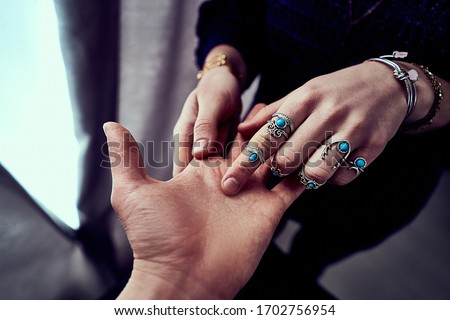 Fortune teller woman wearing silver rings with turquoise stone and bracelets reads palm lines during fortune telling and prediction the future life. Palmistry and divination      