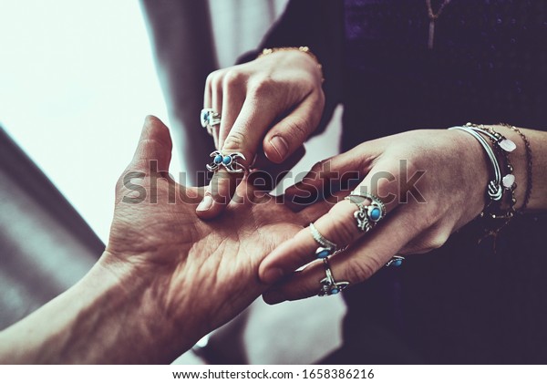 Fortune teller woman wearing silver rings with turquoise stone and bracelets reads palm lines during fortune telling and prediction the future. Palmistry and occult divination      