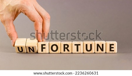 Fortune or unfortune symbol. Businessman turns wooden cubes and changes the concept word unfortune to fortune. Beautiful grey table, grey background copy space. Business, fortune or unfortune concept.