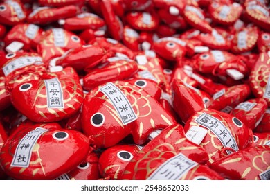 Fortune-teller papers known as 'Omikuji,' crafted in the shape of red fish, at Hikawa Shrine in Kawagoe, Japan. The visible text on the barrels translates to 'Sehikawa Shrine', 'One year of bream' - Powered by Shutterstock