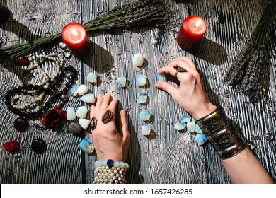Fortuneteller's hands with stone runes, top view. Prediction of the future. Mystic interior. Occult symbols, rosaries, candles, dry lavender