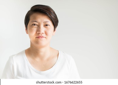 A Forty Ages Asian Woman Portrait Is Smiling; With Her Real Skin Face That Has Freckles, Wrinkles And Furrow; No Makeup On White Background With Copy Space.