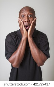 Forty Year Old Bald Black Man Holding His Face With Surprise Expression