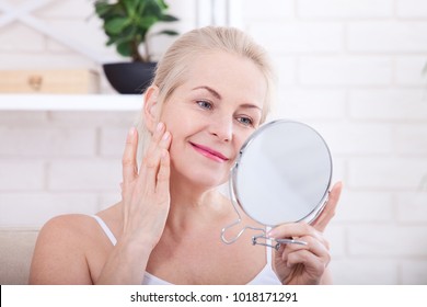 Forty years old woman looking at wrinkles in mirror. Plastic surgery and collagen injections. Makeup. Macro face. Selective focus on the face. Realistic images with their own imperfections.