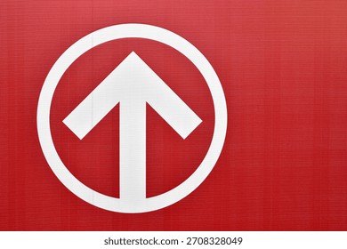 forward direction arrow in circle frame on red textured vinyl banner with copy space, upward arrow icon inside circular border, concepts related to navigation, guidance, progress, and signage design