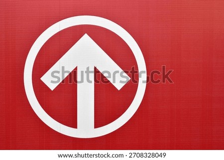 forward direction arrow in circle frame on red textured vinyl banner with copy space, upward arrow icon inside circular border, concepts related to navigation, guidance, progress, and signage design