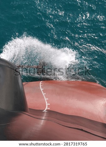 
Forward draft mark on bow of cargo ship with ocean wave and spray, ship hull Plimsoll mark, maritime navigation, vessel displacement measurement, nautical scale on red ship hull
