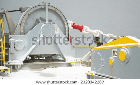 Forward part, windlass and anchor chains of ultra large container ship and stored cargo containers and pacific ocean water  view during bad snowy weather.