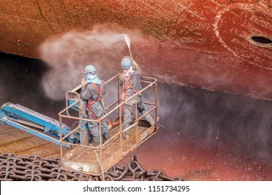 Forward Ship In Floating Dock Worker During Cleaning Surface Of The Deck With High Pressure Water, Process Of Maintenance, On Sherry Picker Car An Removed Rust First Before Sand Blasting And Painting
